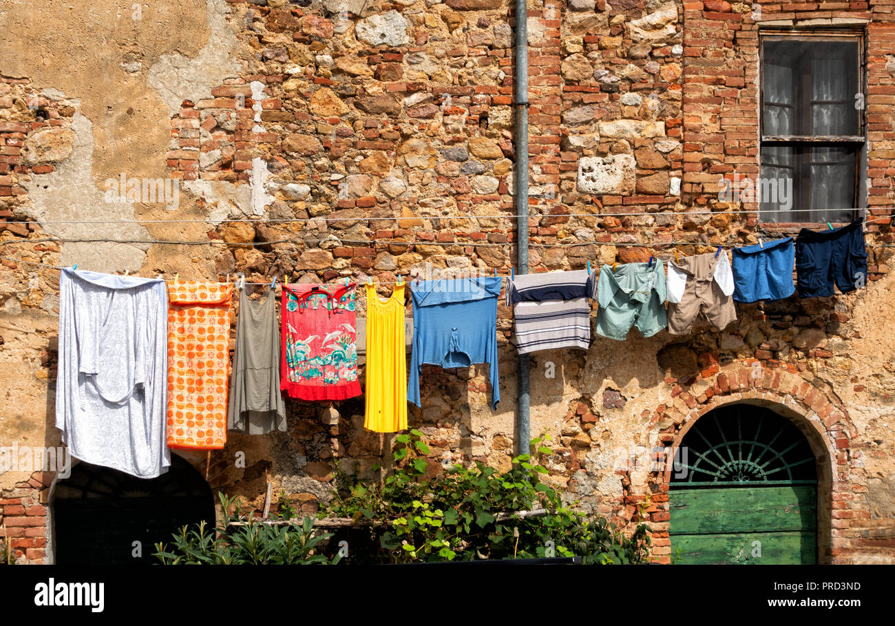 Bunte Kleidung hängend auf einer Wäscheleine, gegen eine Mauer aus Stein; Toskana, Italien Europa Stockfoto