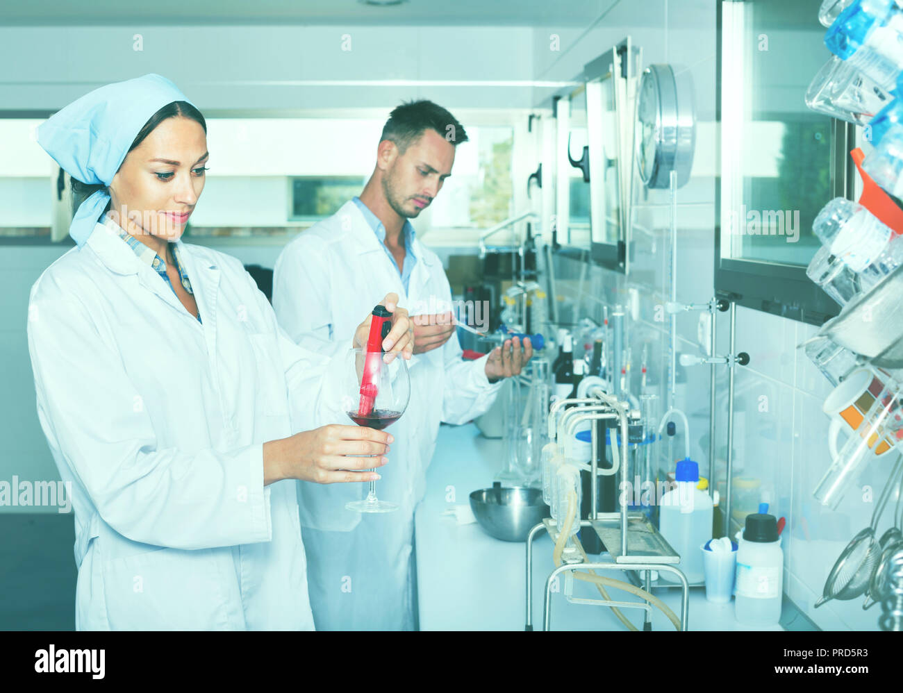 Zwei junge Effiziente lächelnd Forscher im weißen Mantel Kontrolle Wein Säure und Zucker Sättigung im chemischen Labor Stockfoto