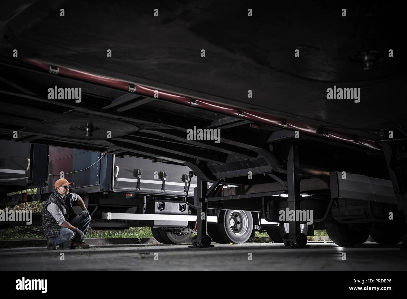 Kaukasische Trucker in seinem 30s-Prüfung ein LKW-Anhänger Unterwagen. Transport Industrie Thema. Stockfoto