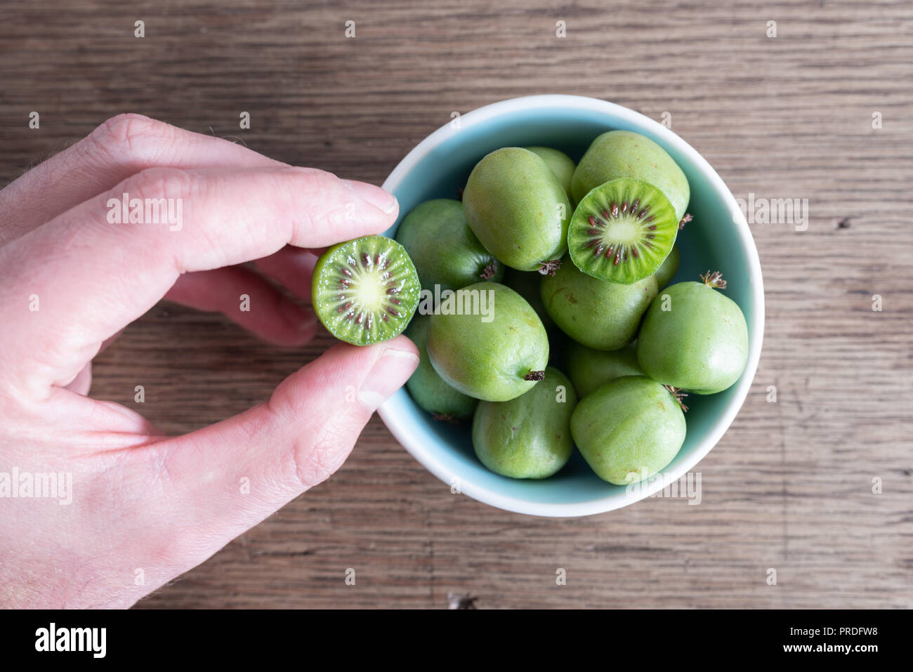 7/8 Handpflückung hardy Kiwi oder kiwi Berry aus Keramik Schüssel auf dem Tisch Stockfoto