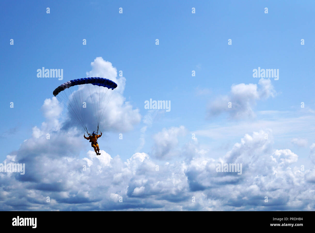 Skydiver unter einem dunkelblauen wenig Überdachung eines Fallschirm auf dem Hintergrund ein blauer Himmel und Wolken, close-up. Silhouette der Fallschirmspringer mit Fallschirm ein Stockfoto