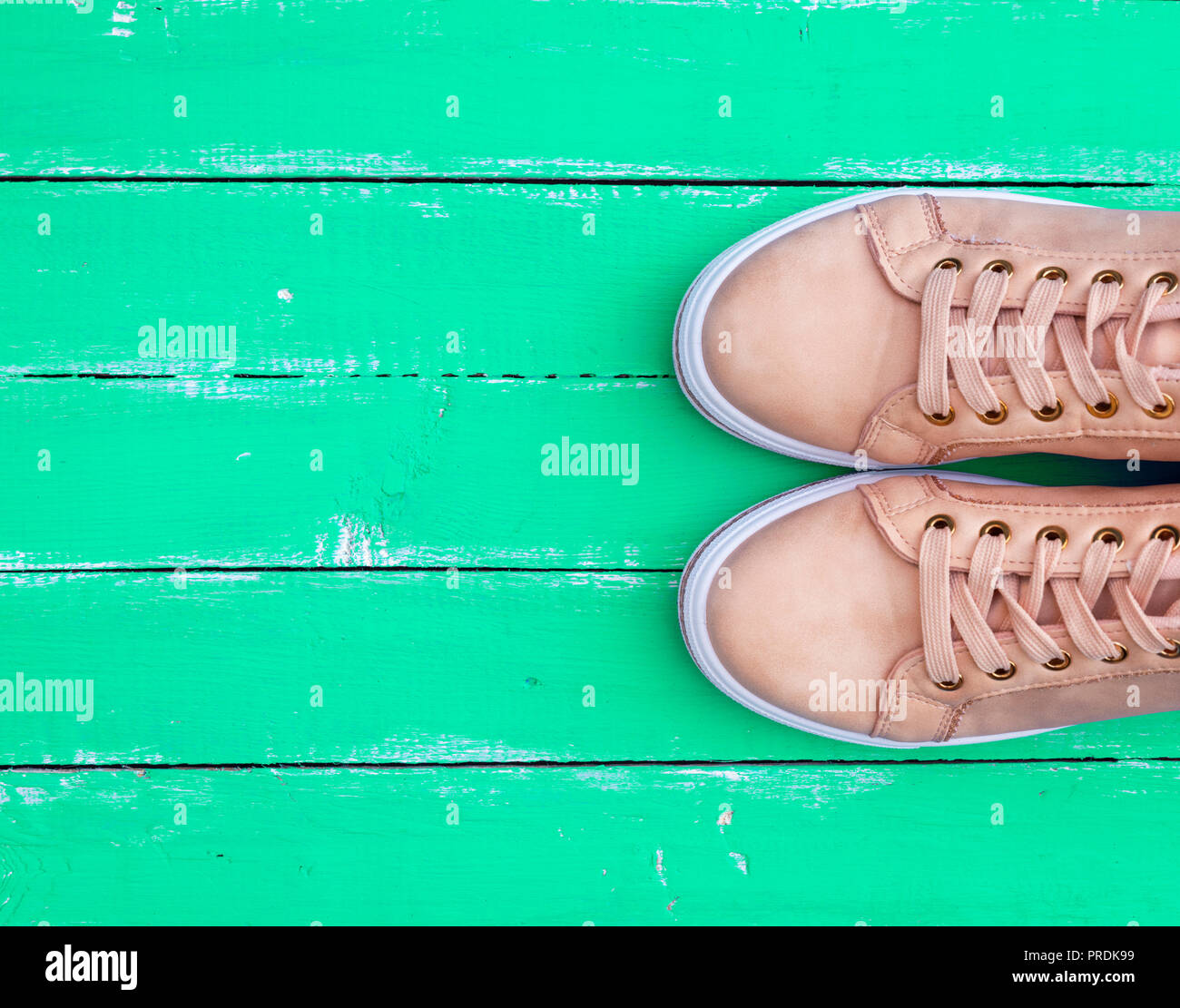 Blick von oben auf ein rosa Paar weiblicher Leder Sneakers mit Schnürung auf der grünen Holz- Hintergrund, kopieren Raum Stockfoto