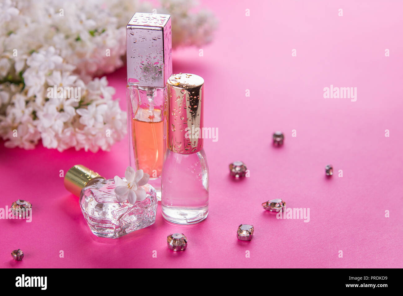 Flaschen Parfüm mit weißen Flieder auf rosa Hintergrund Stockfoto