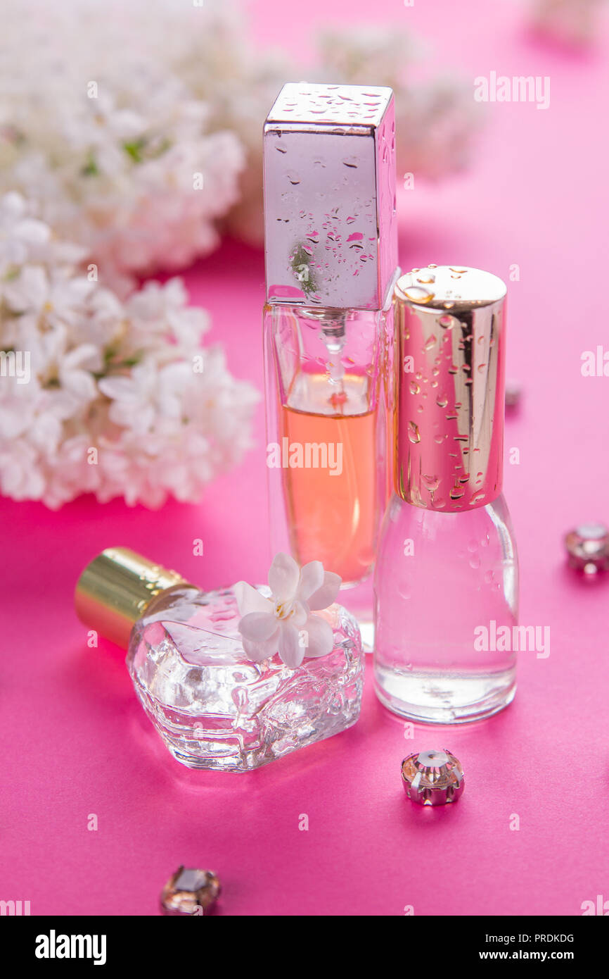Flaschen Parfüm mit weißen Flieder auf rosa Hintergrund Stockfoto
