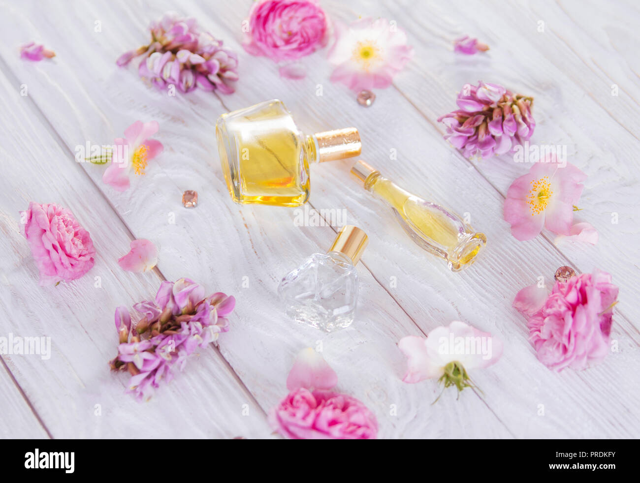 Flaschen Parfüm mit Blumen auf weißem Hintergrund Stockfoto