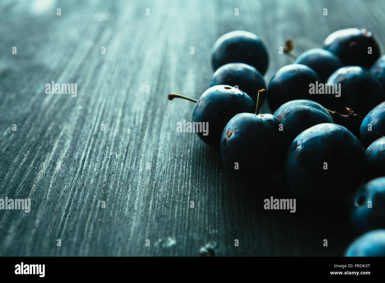 Viele frische Pflaumen auf schwarzem Hintergrund. Stockfoto