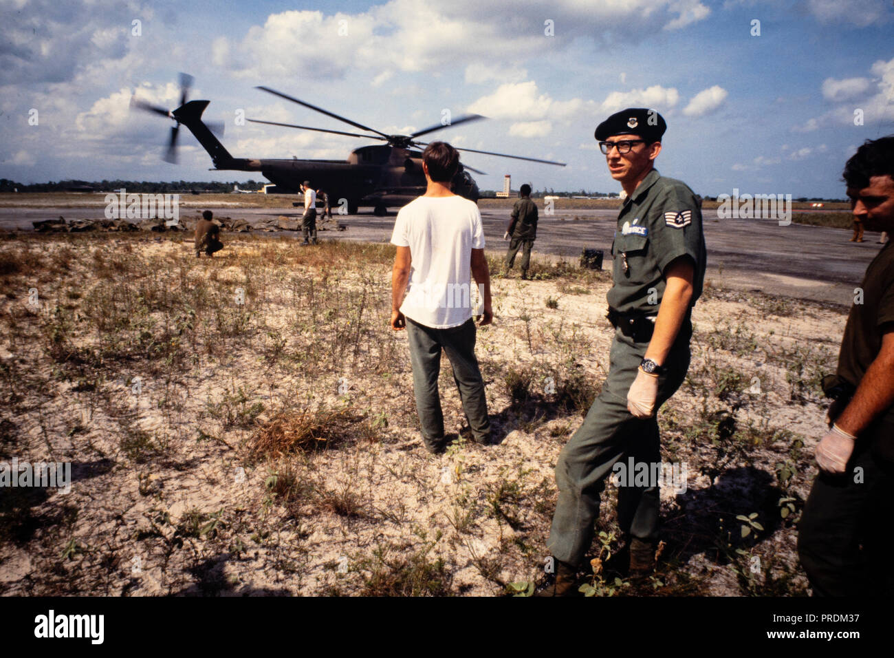 United States Military Personal stehen, mit den amerikanischen Organisationen, die auf dem Rollfeld des Flughafens von der Kult Mord Selbstmord in Jonestown, Guyana für die Rückführung in die USA zurück. Jonestown war eine Siedlung, die von den Völkern Tempel, ein amerikanischer Kult unter der Führung von Reverend Jim Jones, im Norden von Guyana. Es wurde international bekannt, als am 18. November 1978 insgesamt 918 Menschen in der Siedlung starb, auf dem nahe gelegenen Flugplatz in Port Kaituma, und an einem Tempel-run-Gebäude in Georgetown, Guyana Hauptstadt. Stockfoto