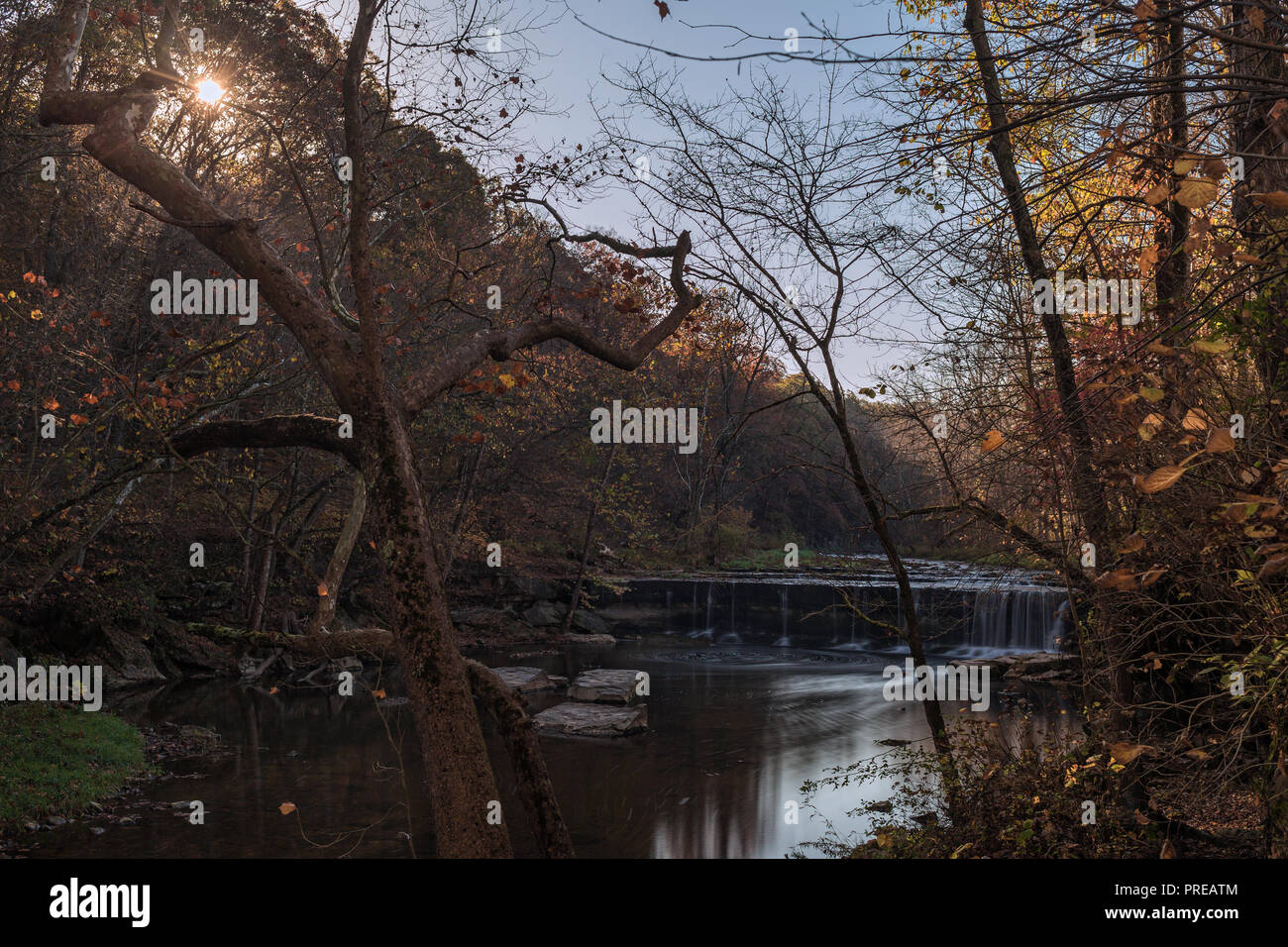 Die Sun Peaks durch eine Reihe von Bäumen auf Clifty Creek in Bartholomew County, IN. Anderson ist in der Hintergrund dieser Herbst Szene. Stockfoto