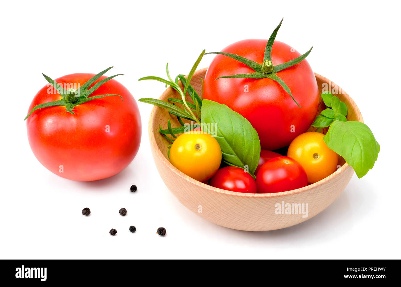 Leckere, frische Tomaten und Kräuter in eine hölzerne Schüssel. Nahaufnahme, auf weißem Hintergrund. Gourmet Essen und gesunde Ernährung. Stockfoto