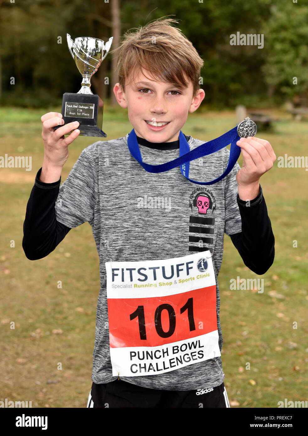 10 Jahre alter Junge stolz seine Medaille und Pokal Anzeige nach dem Gewinn einer 2,5 km querfeldein laufen Rennen, Hindhead, Surrey, Großbritannien. Sundy, 30. September 2018. Stockfoto