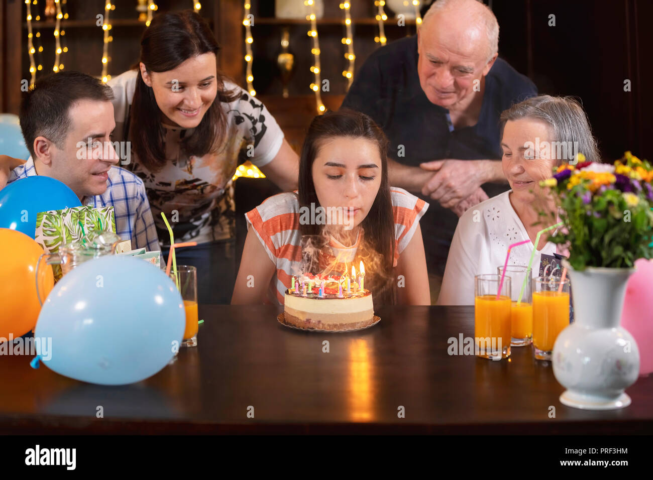 Happy Family feiern Teenager Tochter und Enkelin Jubiläum. Das Mädchen bläst die Kerzen auf der Geburtstagstorte. Menschen hapiness und zu feiern. Stockfoto