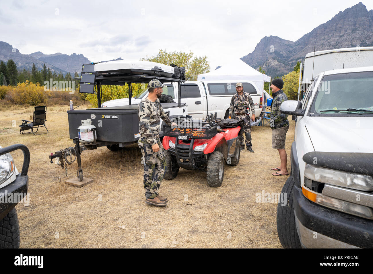 Erwachsenen männlichen Jäger sammeln sich um Base Camp, über Pläne für den Tag. Lkw und 4 x 4 Wheelers im Foto. Das Tragen von camouflage Stockfoto