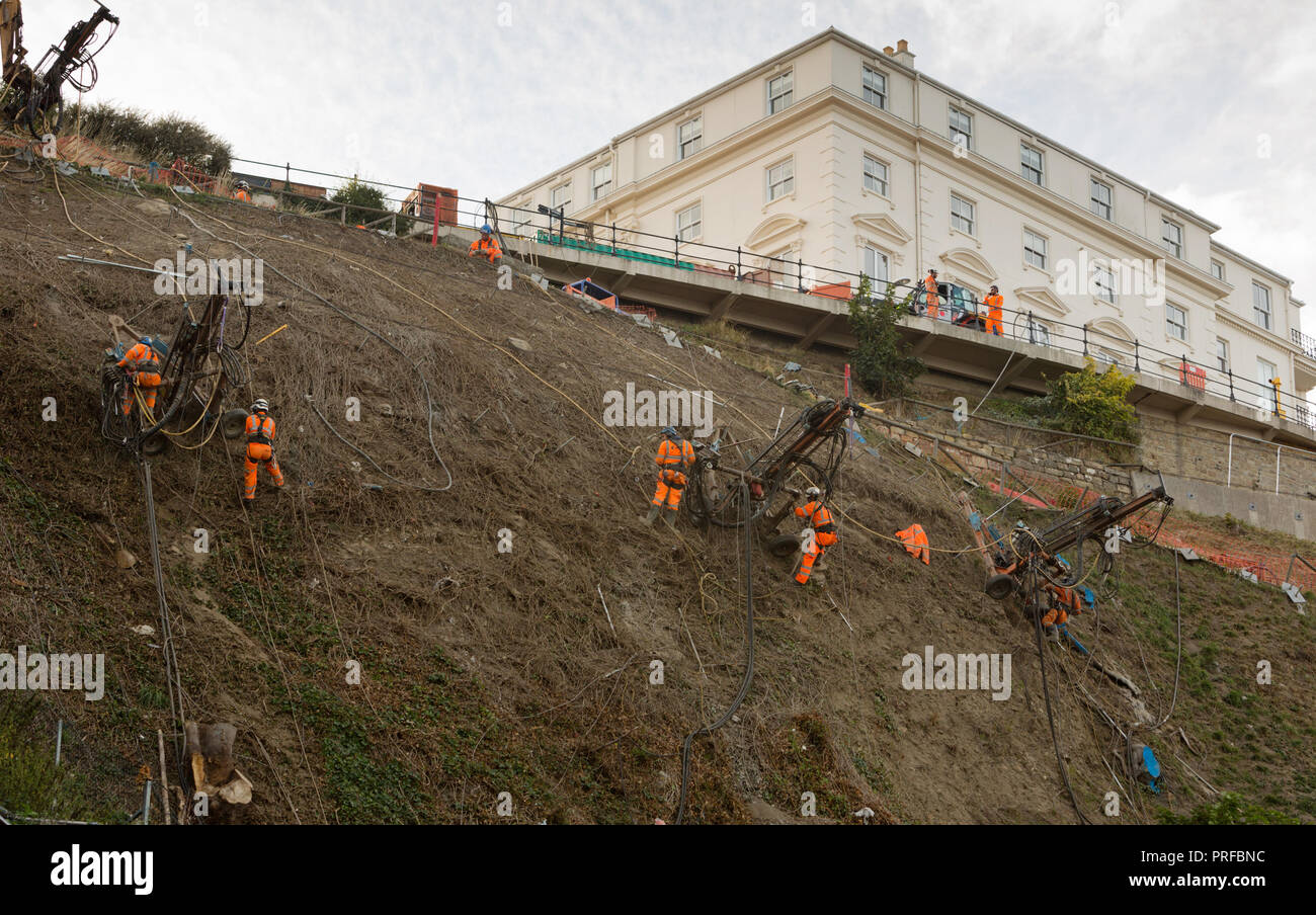 Bauingenieure in Kabelbäumen durch Kabel an der Felswand in Scarborough Arbeiten unterstützt. hingegen ungeschärft Stockfoto