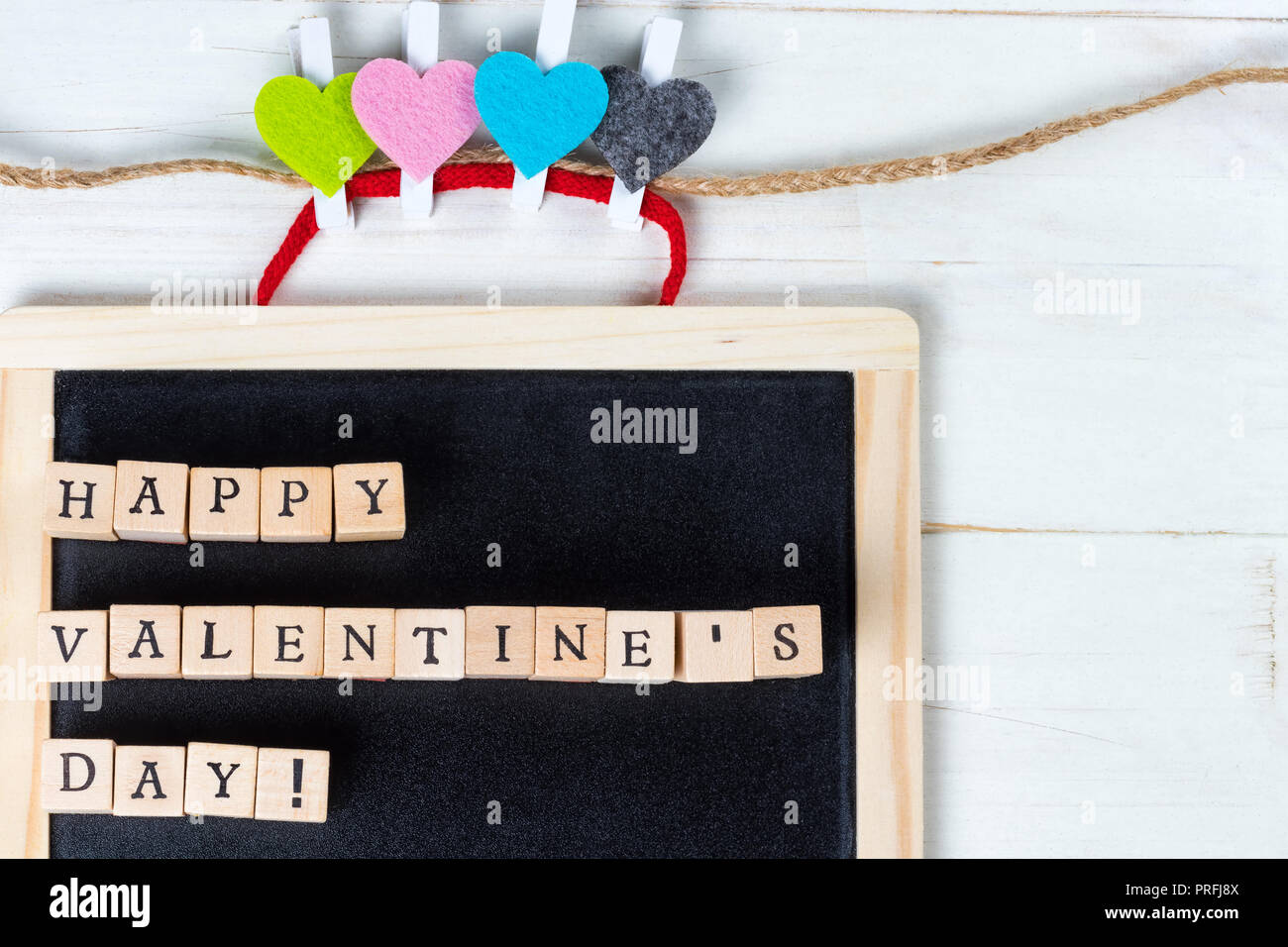 Happy Valentines Tag Bildunterschrift auf einer Tafel mit bunten Herzen auf ein Garn string. Kopieren Sie Platz auf der rechten Seite. Stockfoto