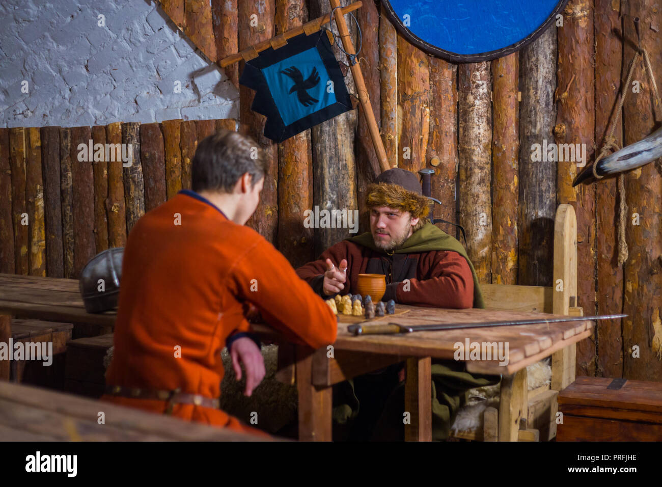 Zwei Männer in russischen ethnischen Anzug spielen mittelalterliche beliebte strategy Board Game - tafl. Folk, Wettbewerb und traditionellen Konzept Stockfoto