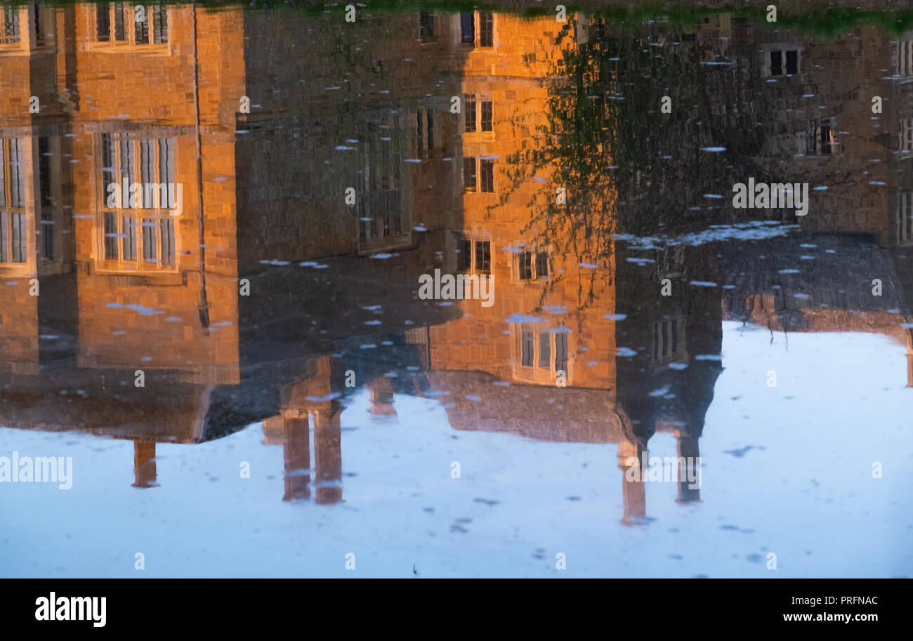 Broughton Schloss, in der Nähe von Banbury, der Heimat der Fiennes Familie im goldenen Abendlicht mit Reflexionen im Wasser des Grabens. Für die Öffentlichkeit zugänglich Stockfoto