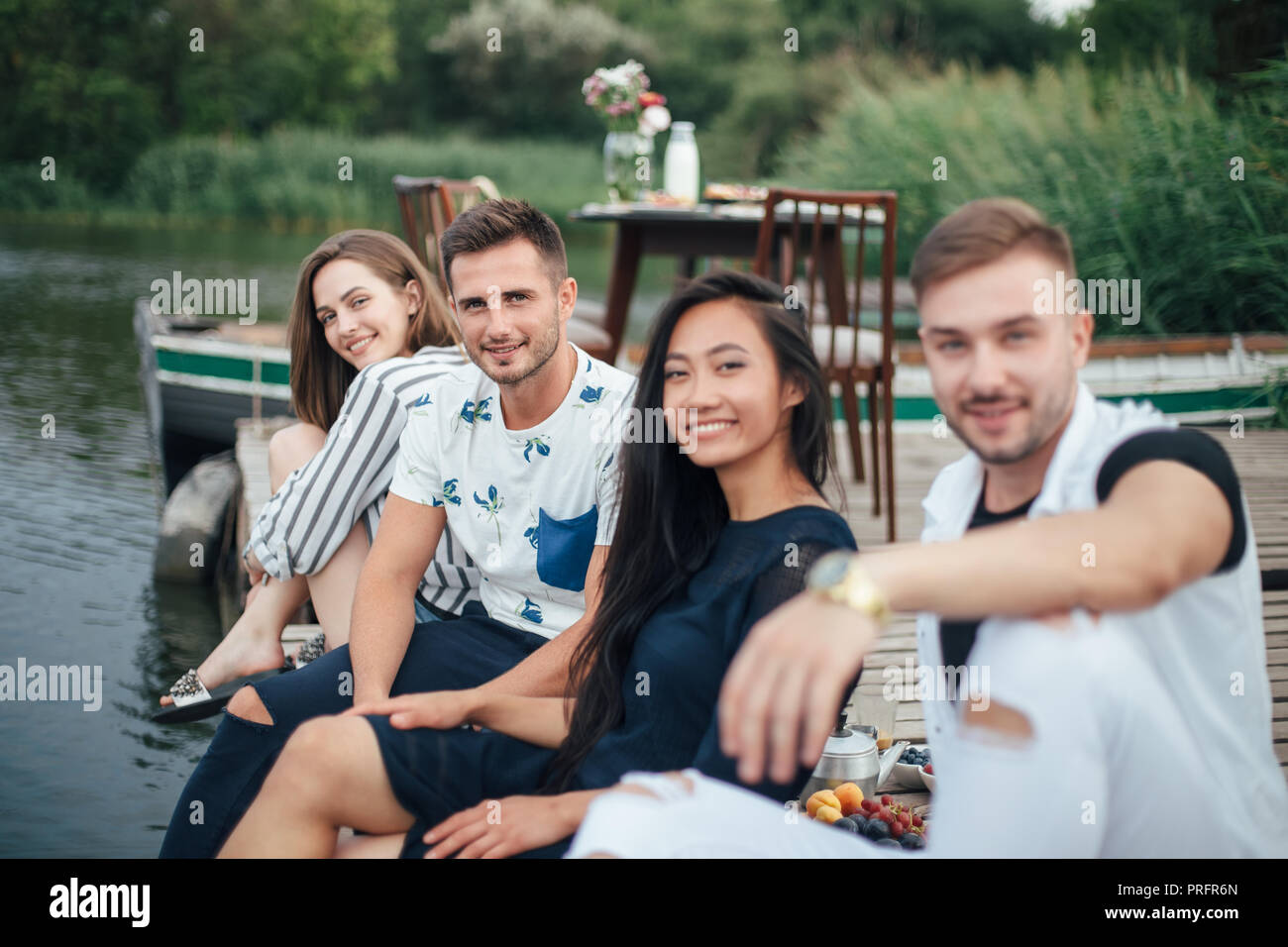 Gruppe der glückliche junge Freunde entspannen auf Fluß Pier. Sommer Urlaub Konzept Stockfoto