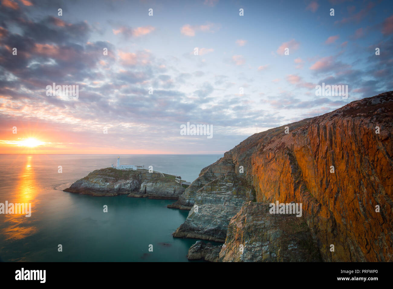 Abend Landschaft schoss der untergehenden Sonne und dramatischer Abendhimmel mit Blick aufs Meer in Richtung South Stack Lighthouse, Anglesey, Nordwales. Stockfoto