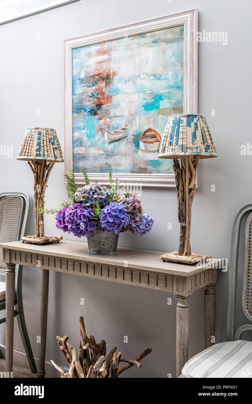 Driftwood Lampen auf der Konsole mit Kunstwerken und Blumen Stockfoto