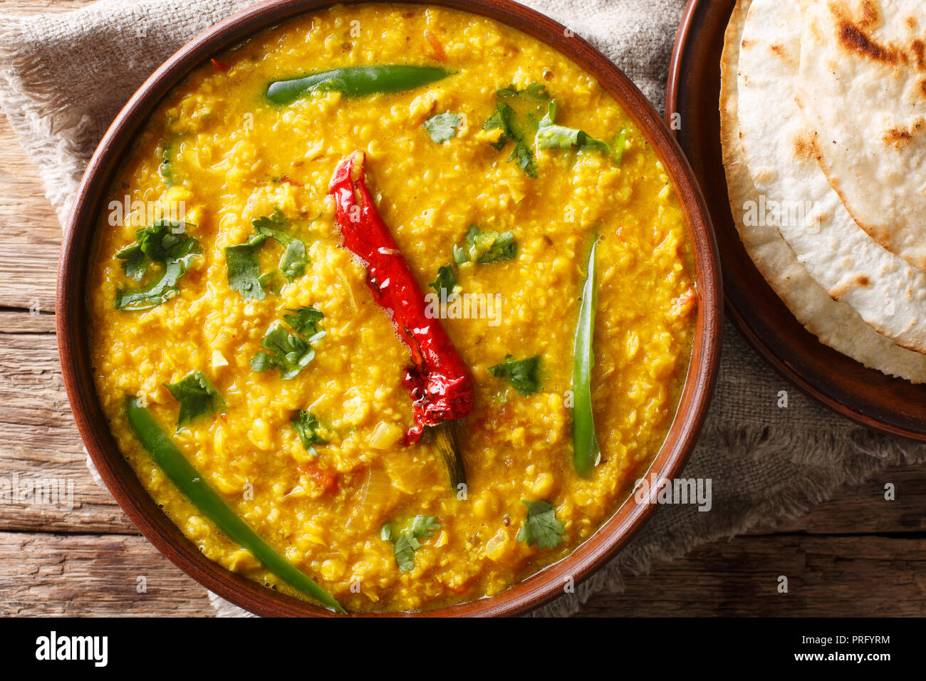 Linsensuppe Dal Tadka in eine keramische Schüssel mit Naan Brot auf einem hölzernen Hintergrund. Schließen oben. horizontal oben Ansicht von oben Stockfoto