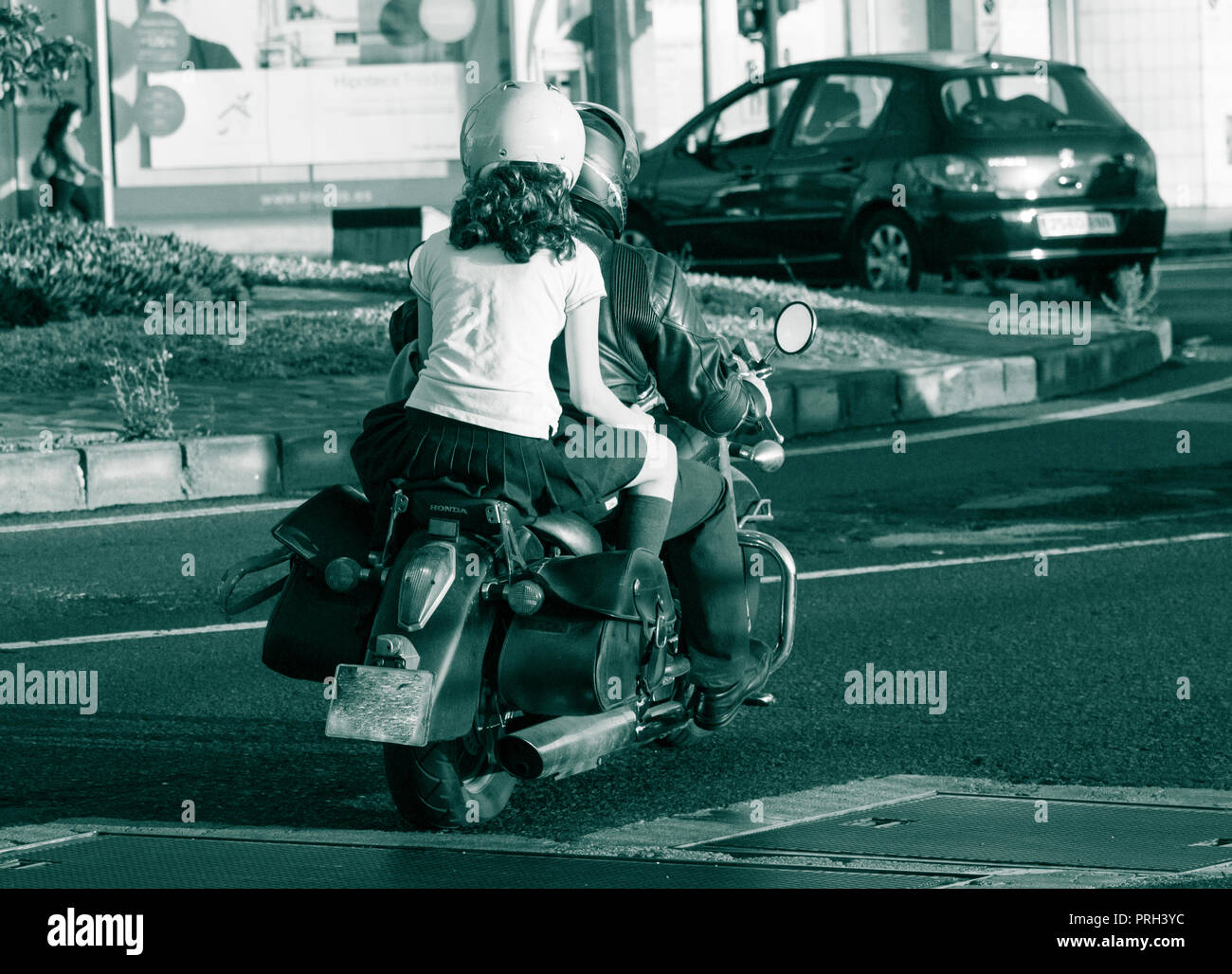 Mädchen in Schuluniform reiten Sozius auf Motorrad Stockfoto