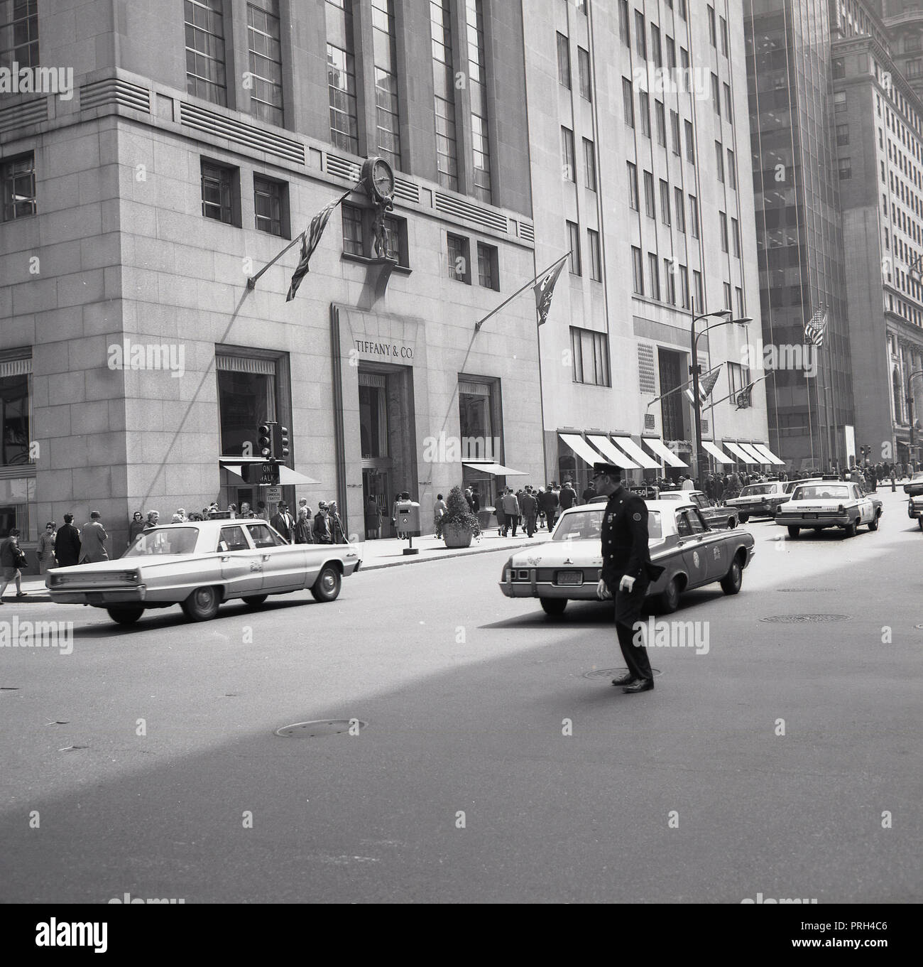 1960, historische, New York City Polizeioffizier Überwachung des Verkehrs auf der 5th Avenue. An der Ecke ist der Sitz von Luxus Juwelier Tiffany & Company. Stockfoto