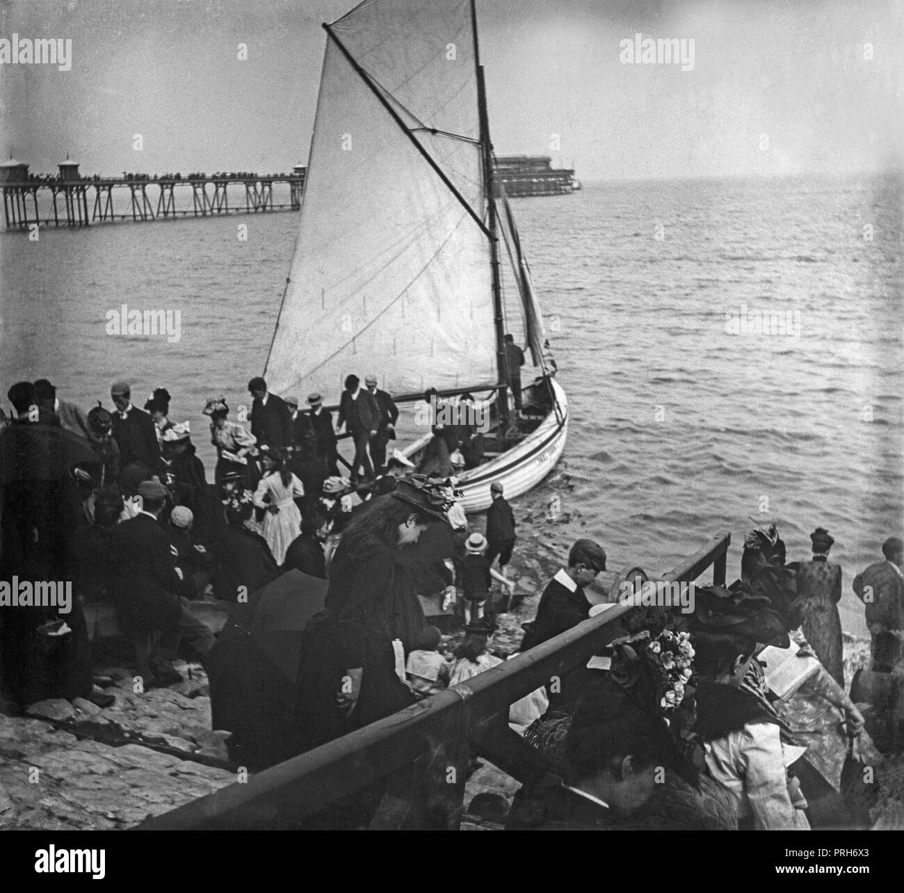 Ein spät-viktorianischen Foto, Gruppen von Menschen, einige Aussteigen aus einem kleinen Boot, und mit einem Pier im Hintergrund, einem Badeort in England. Stockfoto