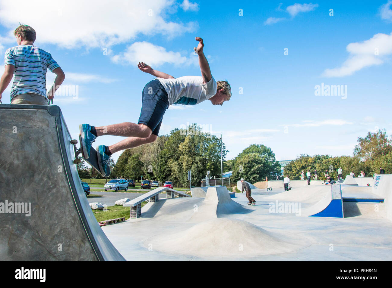 Ein Skateboarder Durchführen einer Skateboard Trick auf ein Viertel am Konkreten Wellen in Newquay in Cornwall. Stockfoto