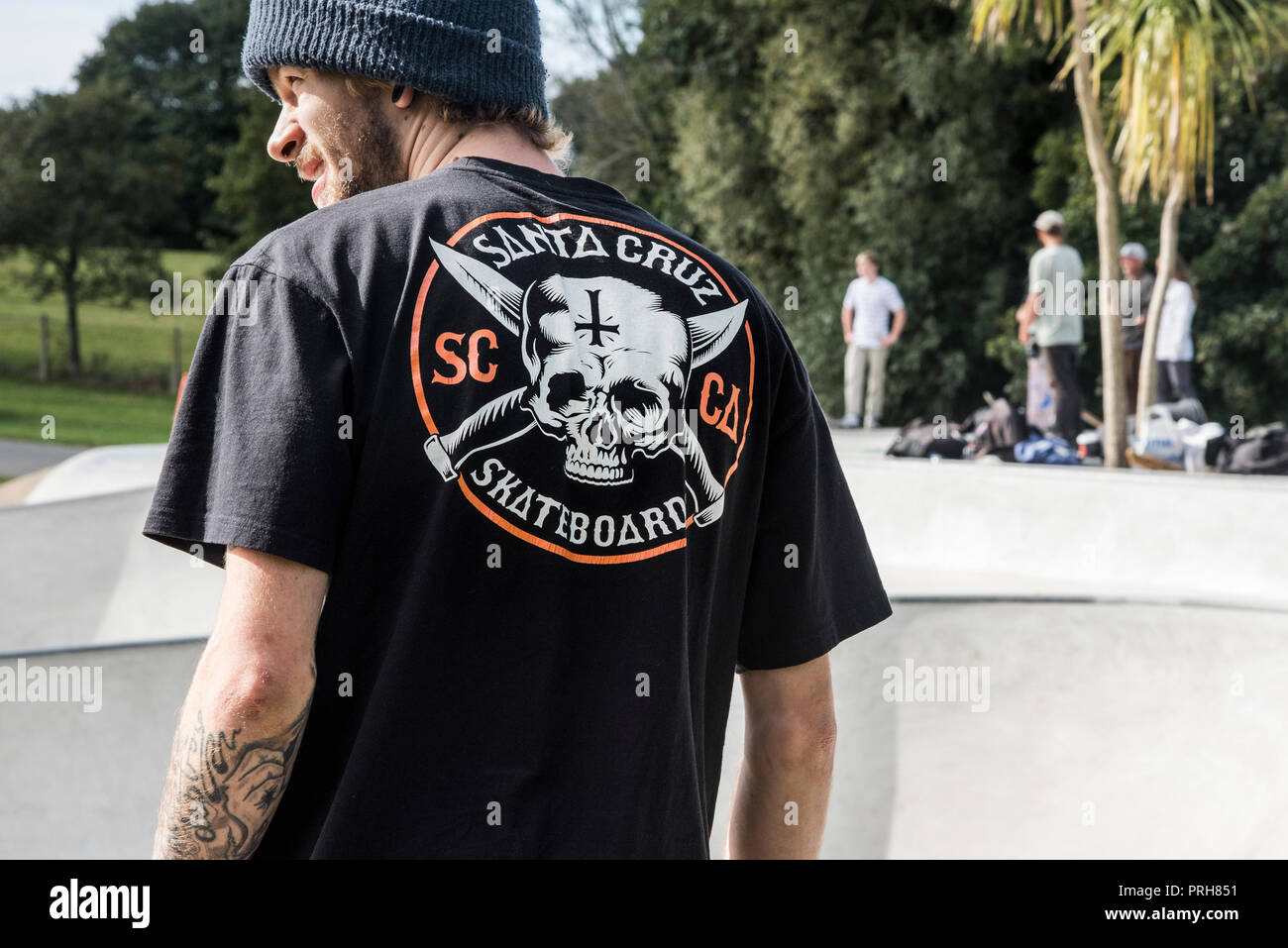 Die Ansicht von hinten von einem Skateboarder trägt ein T-Shirt mit einem Santa Cruz Skateboards Logo. Stockfoto