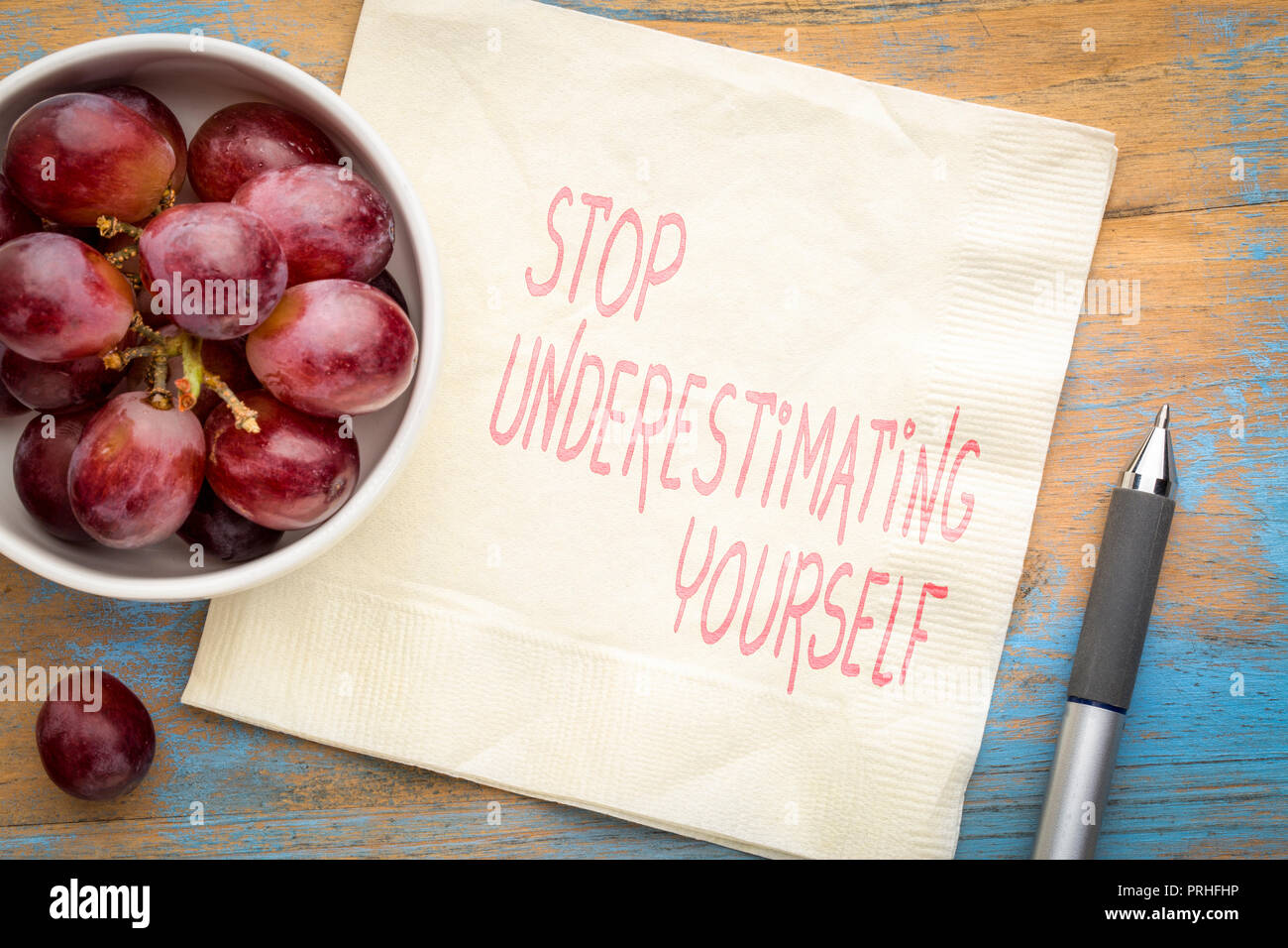 Stop unterschätzen Selbst - inspirational Handschrift auf eine Serviette mit frischen Weintrauben Stockfoto