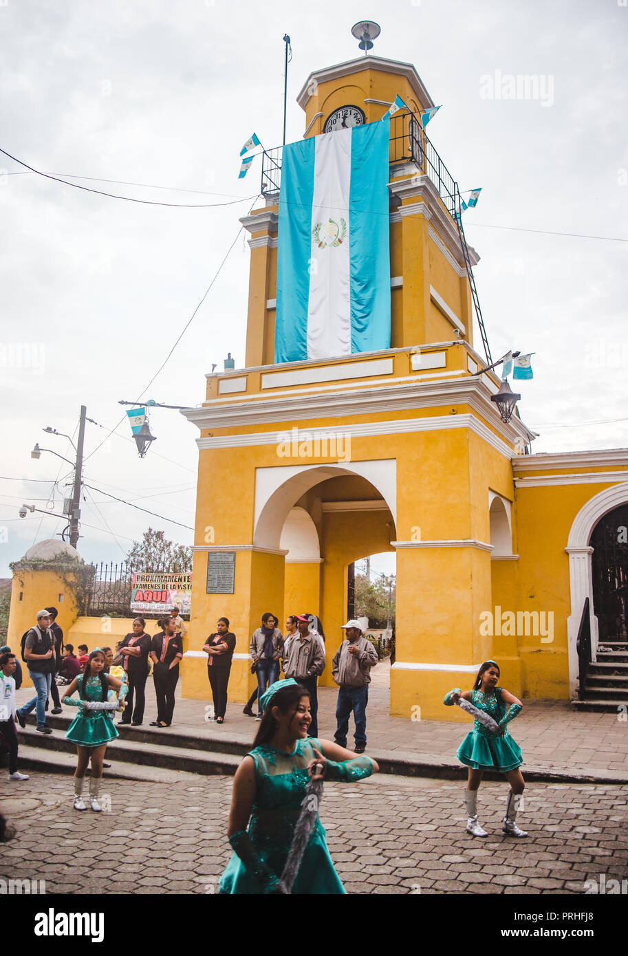 Marching Band Tänzer Parade in einer Prozession unter einem guatemaltekischen Flagge in Ciudad Vieja, eine kleine Stadt Antigua Stockfoto