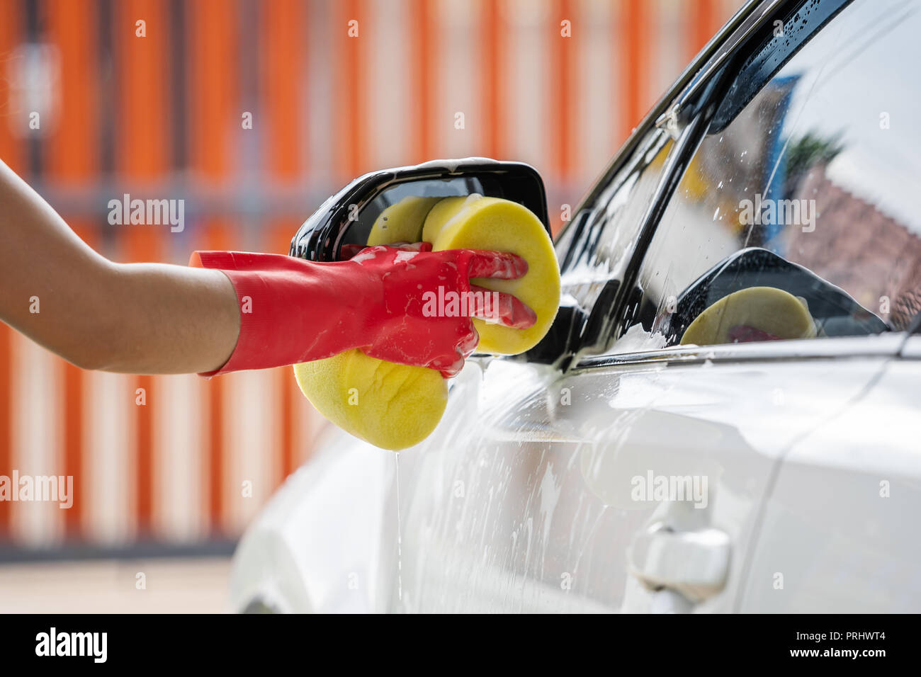 Hand mit Schwamm waschen Außenspiegel eines Pkw Stockfoto