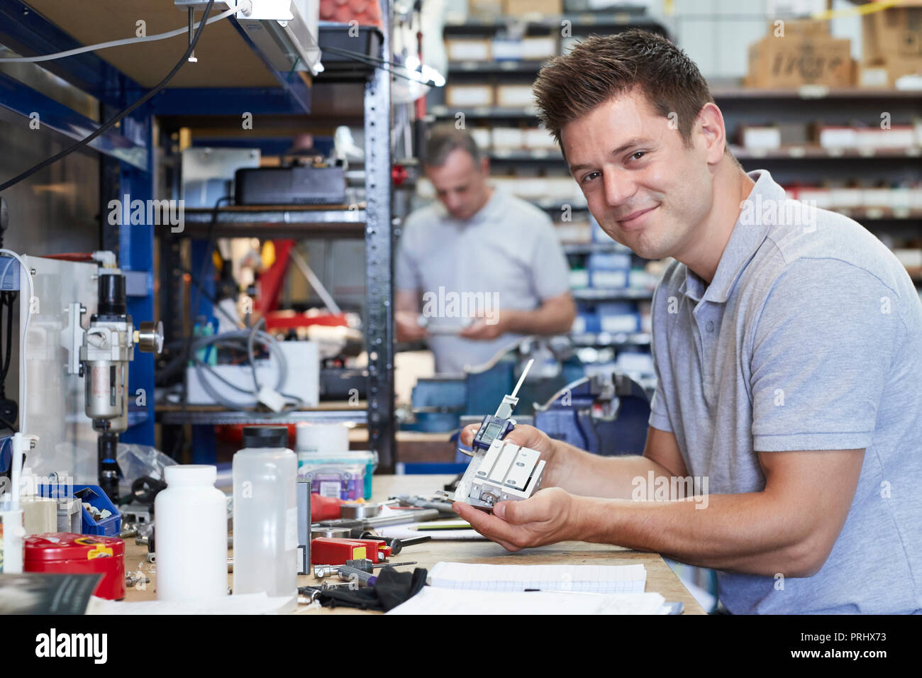 Portrait von Ingenieur im Werk Messen Komponente an der Werkbank mithilfe eines Mikrometers Stockfoto