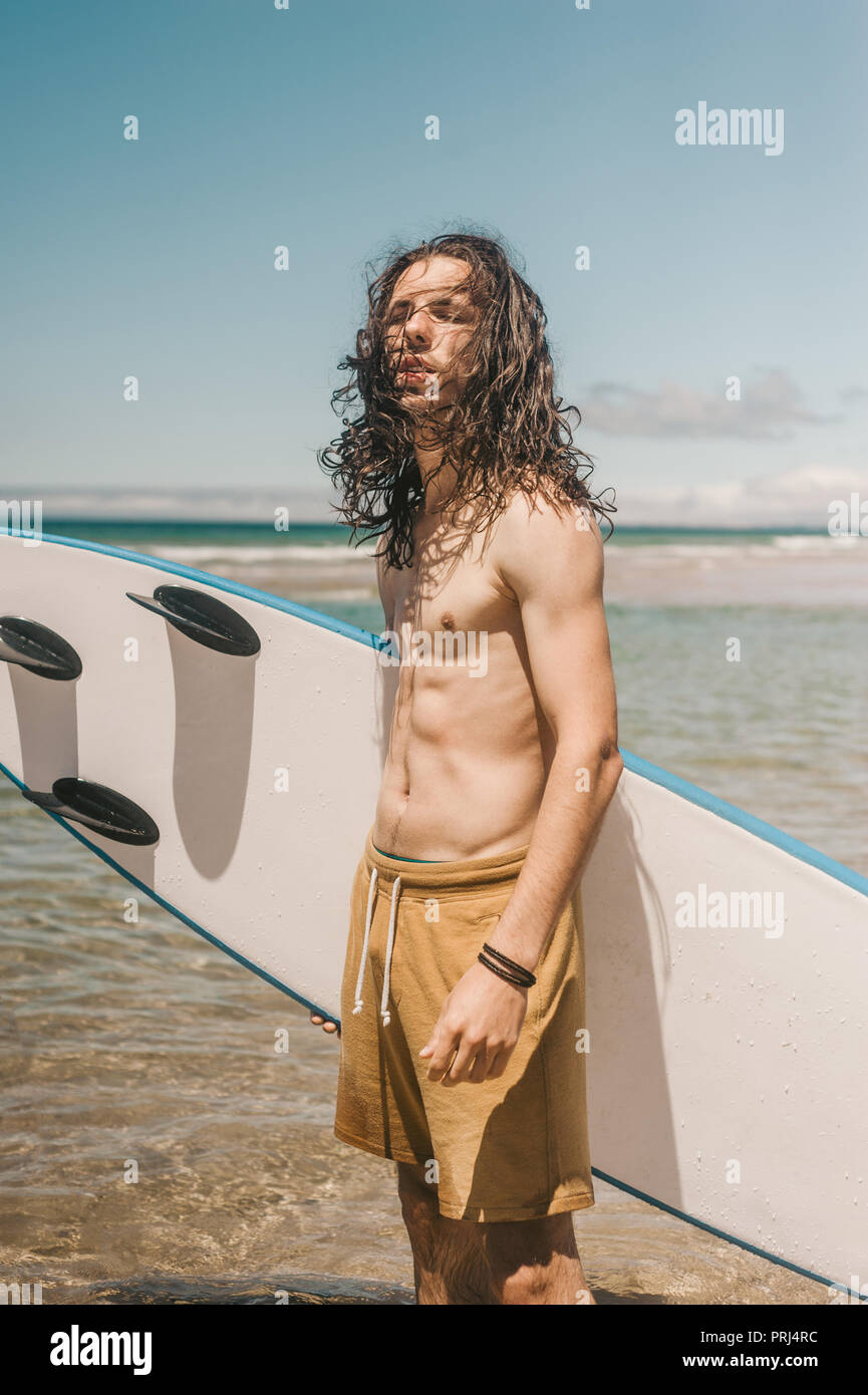 Porträt eines jungen Mannes mit Surfbrett stehend im Ozean auf Sommer Tag Stockfoto