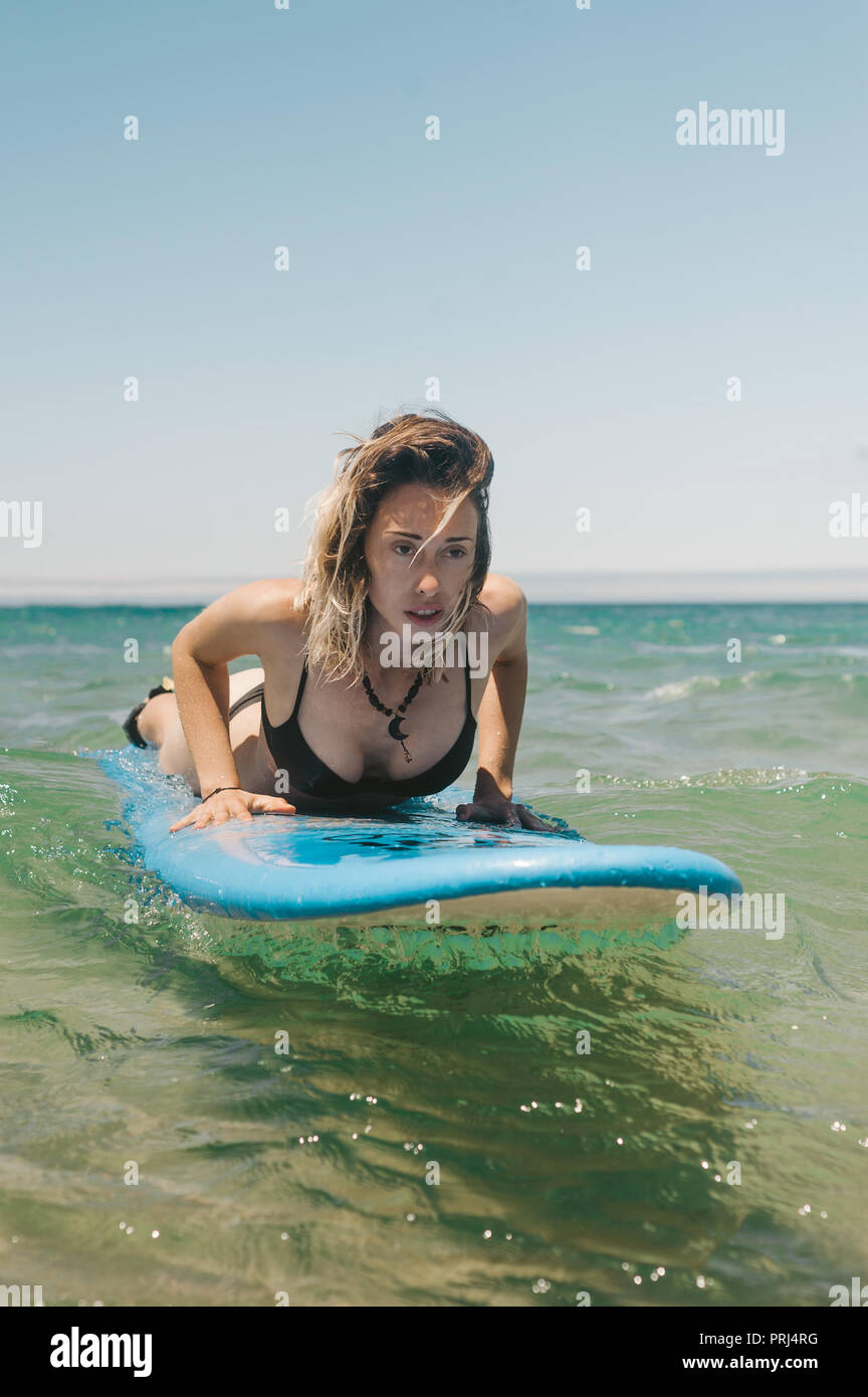 Junge Frau im Bikini liegen auf Surfen im Ozean Stockfoto