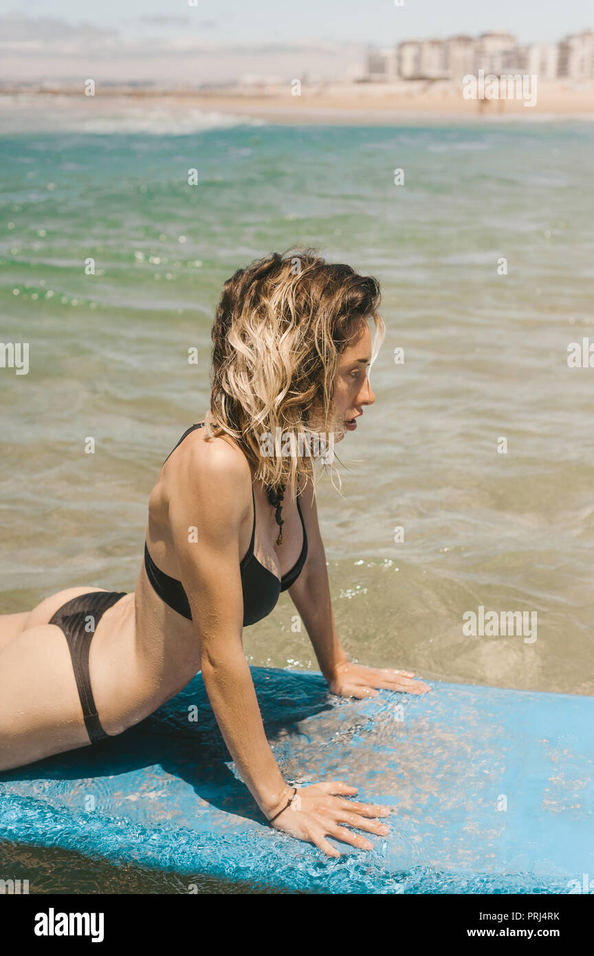 Seitenansicht der jungen Frau im Bikini liegen auf Surfen im Ozean Stockfoto