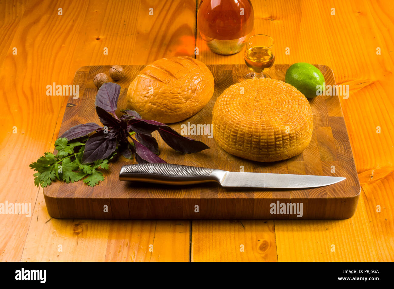 Immer noch leben - nationale Adyghe Käse Hausgemachte auf einem Schneidebrett mit Messer, mit Basilikum, Petersilie, Kalk, Sesamöl, Macadamianüsse, Chili, auf Stockfoto