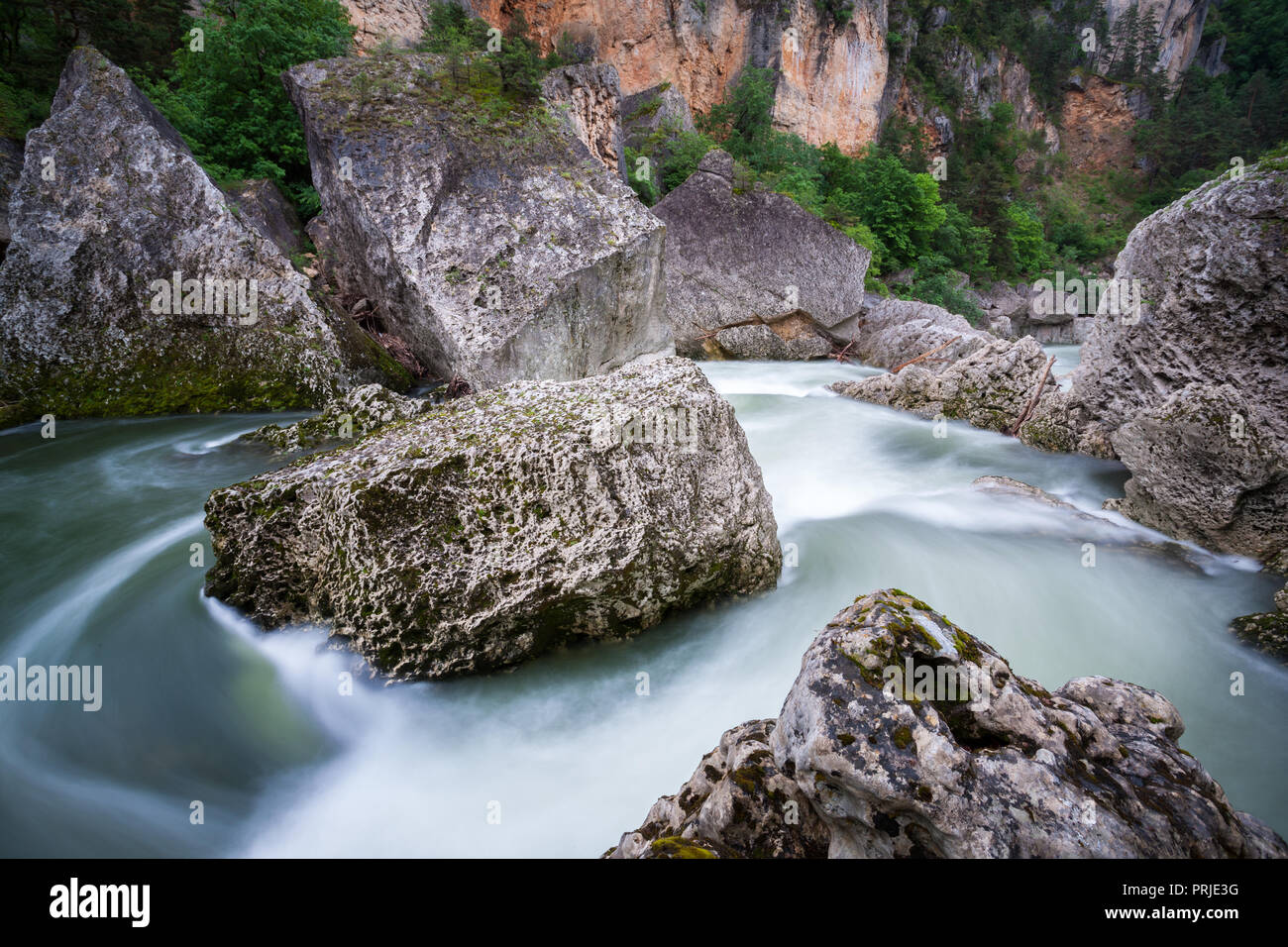 Schnell fließenden Wasser um riesige Felsbrocken und Fluss Steine in den Gorges du Tarn Aveyron Frankreich Stockfoto