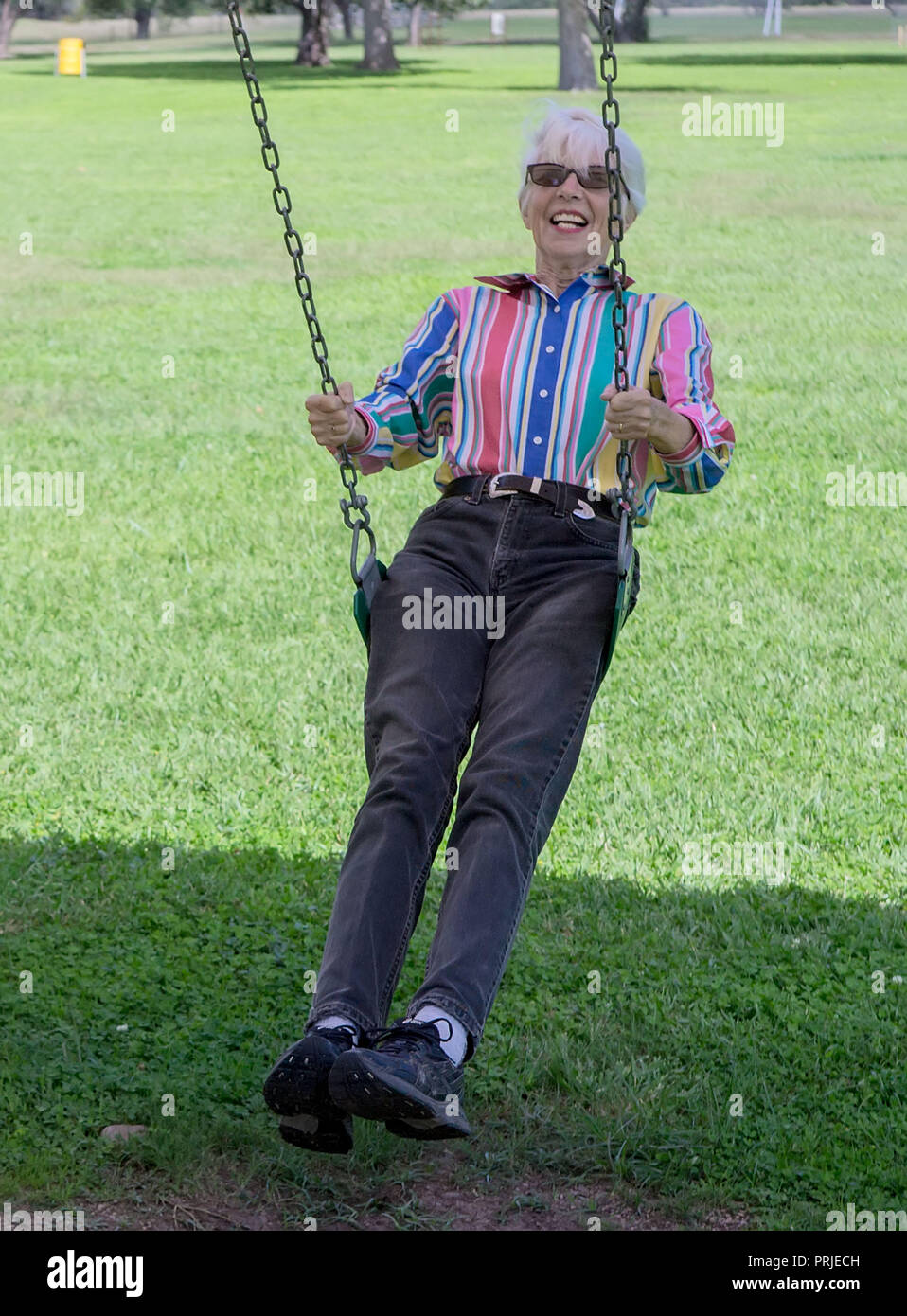 Ein älterer Bürger Frau genießen schwingen in einem öffentlichen Park in Far West Texas. Stockfoto
