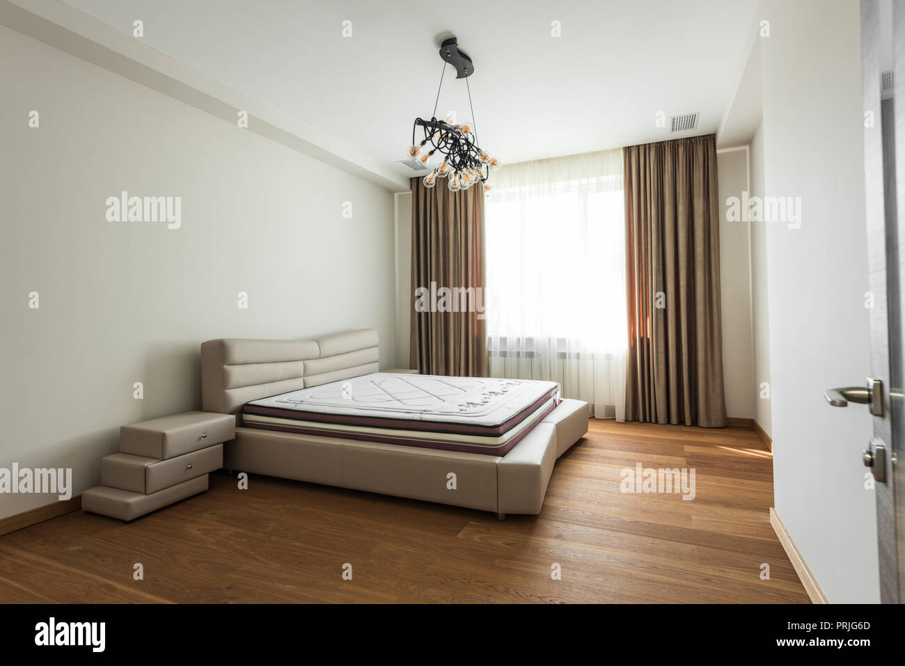 Innere leere Schlafzimmer mit einem großen Fenster und die Matratze auf dem Bett Stockfoto