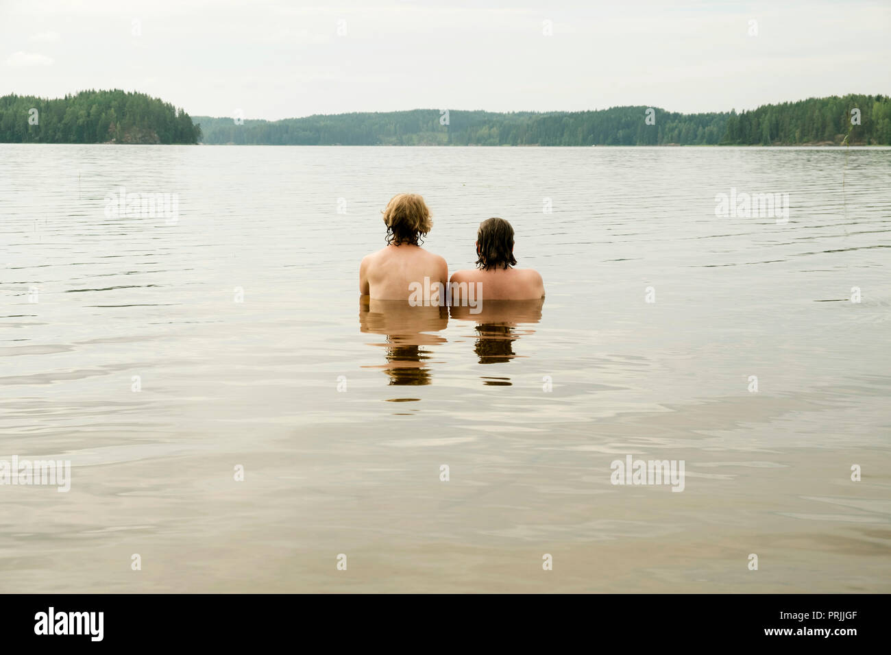 Zwei junge Frauen, die im Wasser sitzen, der Blick in die Ferne, See Gunnern, Gunnarskog, Arvika, Värmland, Schweden Stockfoto