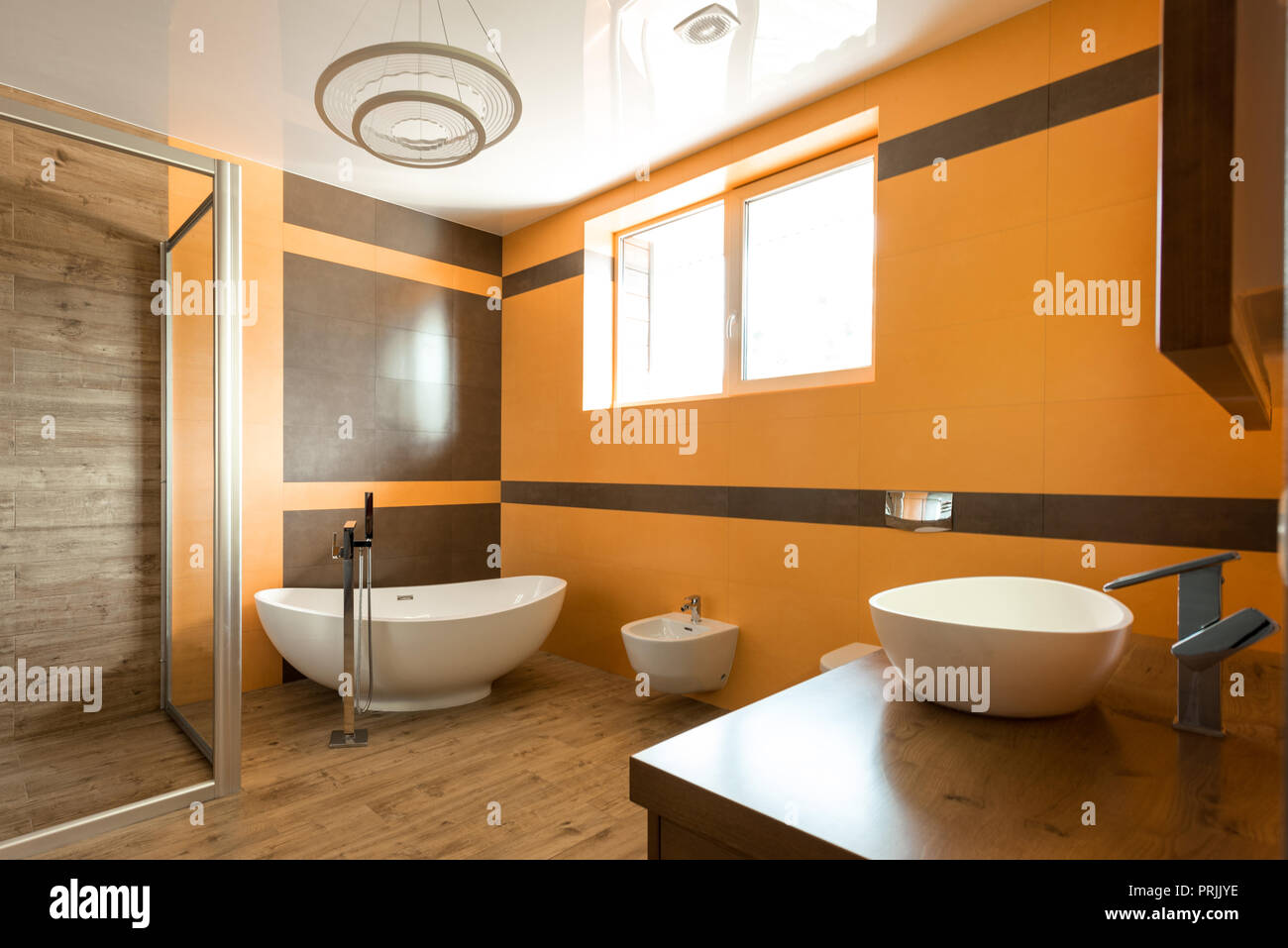 Innenraum der Badezimmer in Orange und Weiß mit Badewanne, Waschbecken und Bidet Stockfoto