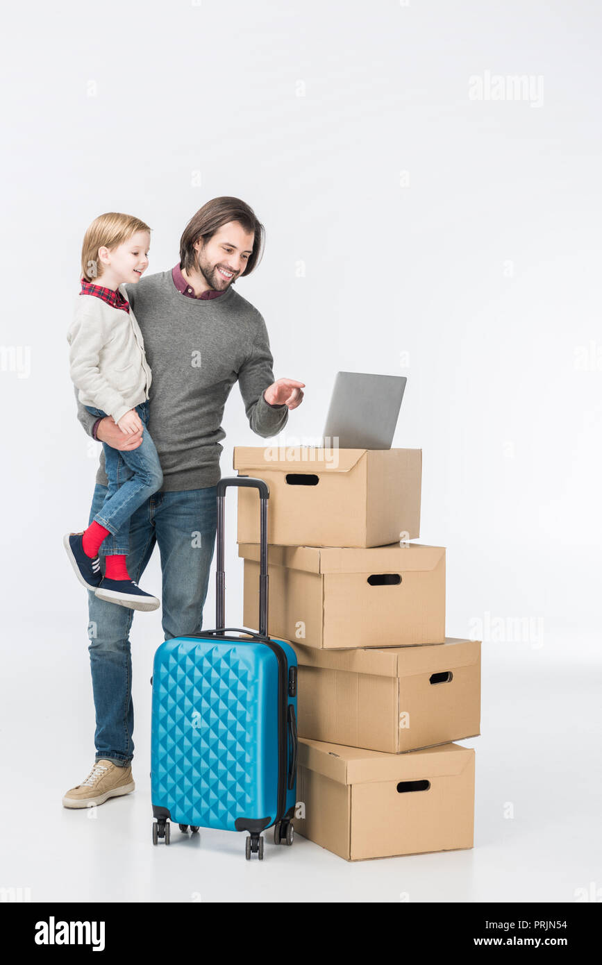 Gerne Vater mit Sohn mit Laptop auf Kartons isoliert auf weißem Stockfoto