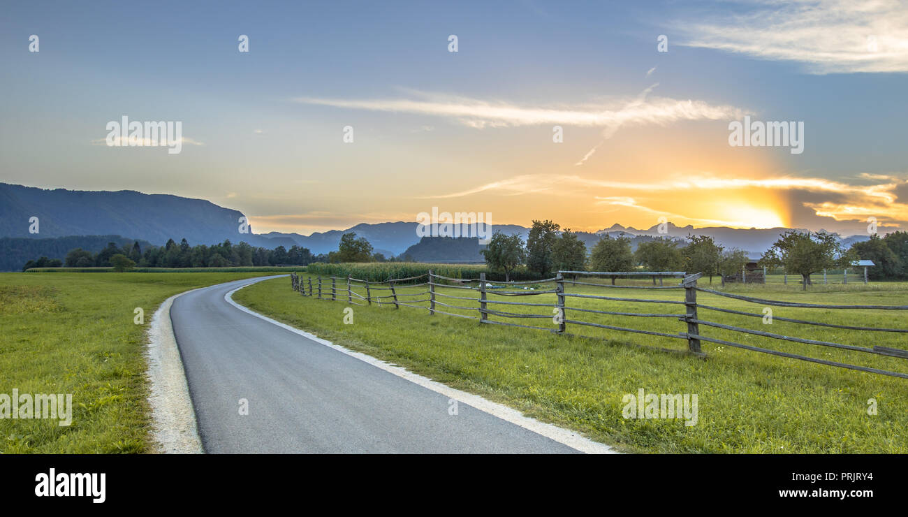 Sekundäre Straße durch slowenische Landschaft Landschaft mit den Julischen Alpen im Hintergrund in der Nähe von Bled Stockfoto