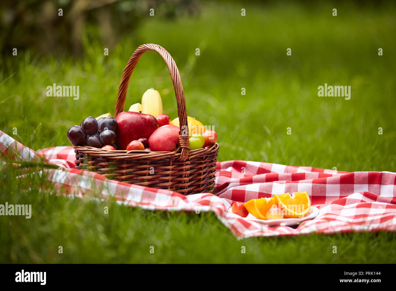 Sortierte Früchte in einem Korb für Picknick auf Gras. Stockfoto