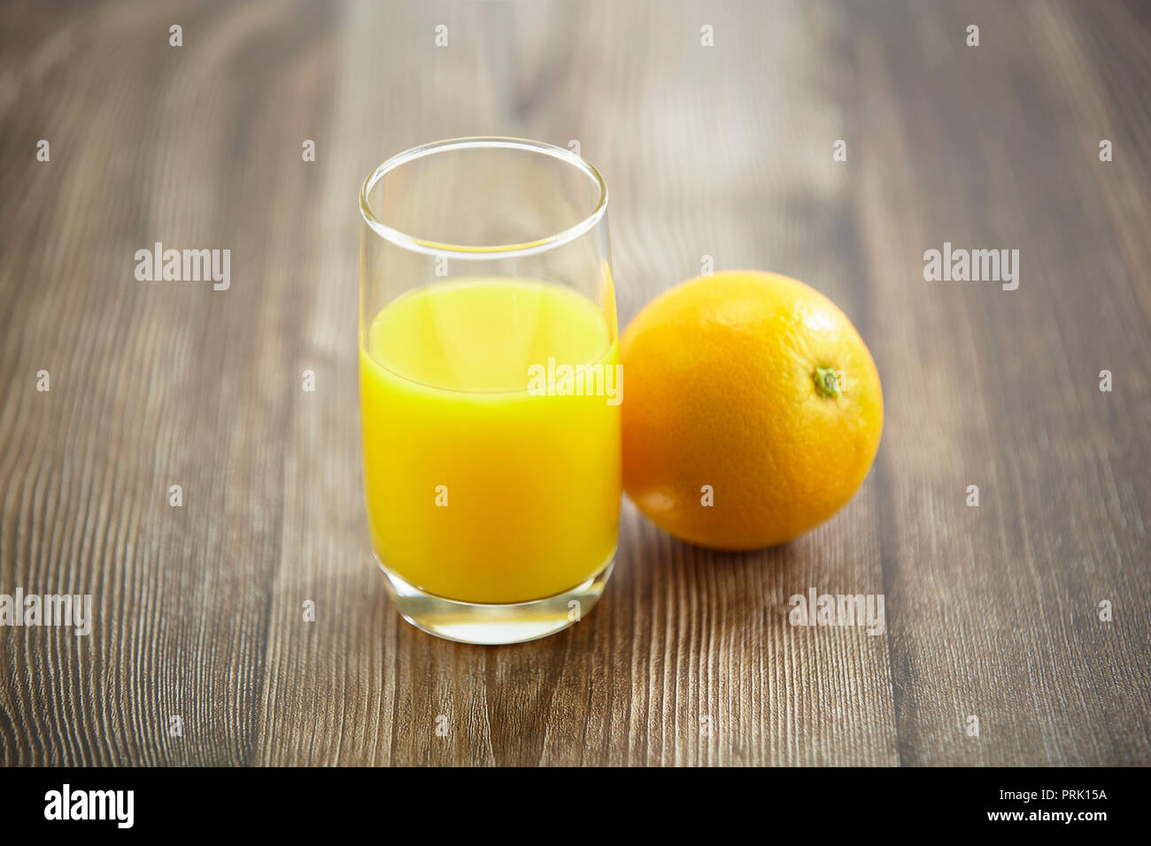 Eine orange und ein Glas Orangensaft auf der Oberfläche des Holzes. Stockfoto