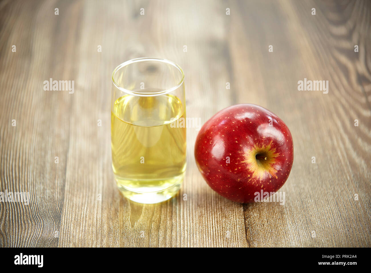 Ein Apfel und ein Glas Apfelsaft auf der Oberfläche des Holzes. Stockfoto