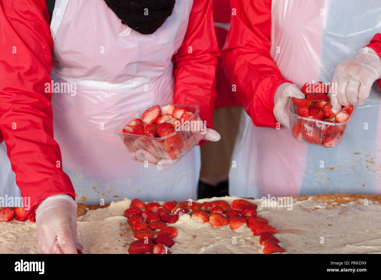 Professionelle Frauen Vorbereitung eine große Erdbeerkuchen Stockfoto