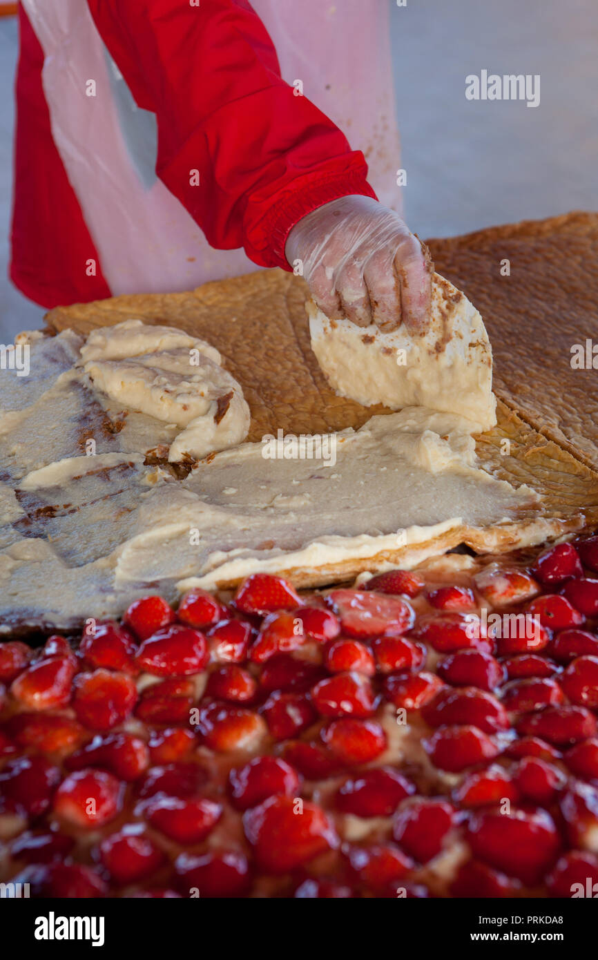 Professionelle Frauen Vorbereitung eine große Erdbeerkuchen Stockfoto