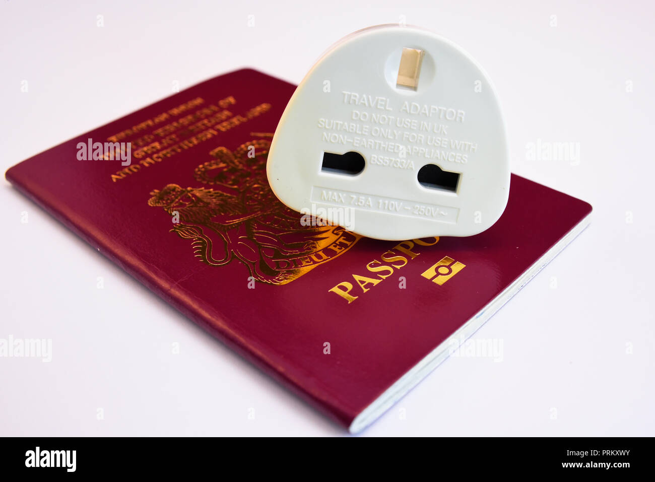 Europäische Union Vereinigtes Königreich von Großbritannien und Nordirland Burgund biometrischen Reisepass mit Travel Adapter Stecker. Auf weissem Hintergrund Stockfoto
